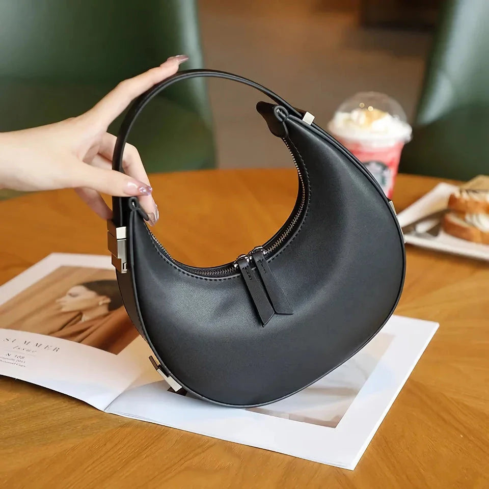 Elegant leather shoulder bag with a unique half-moon shape, designed for the modern British woman