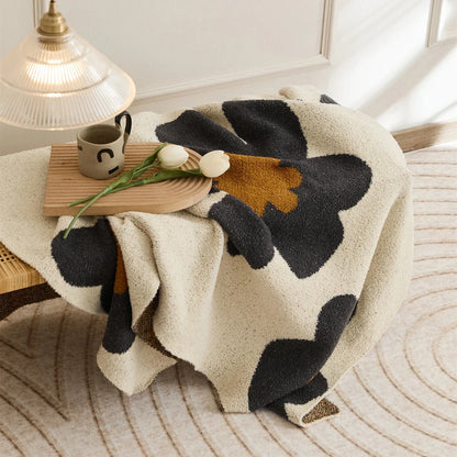 Cosy floral knitted throw blanket in red, grey, and orange shades - a high-quality microfibre accessory for year-round comfort and style