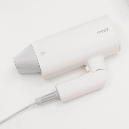 Compact and portable hair dryer with foldable handle, two-speed settings, and multiple nozzle positions for versatile styling