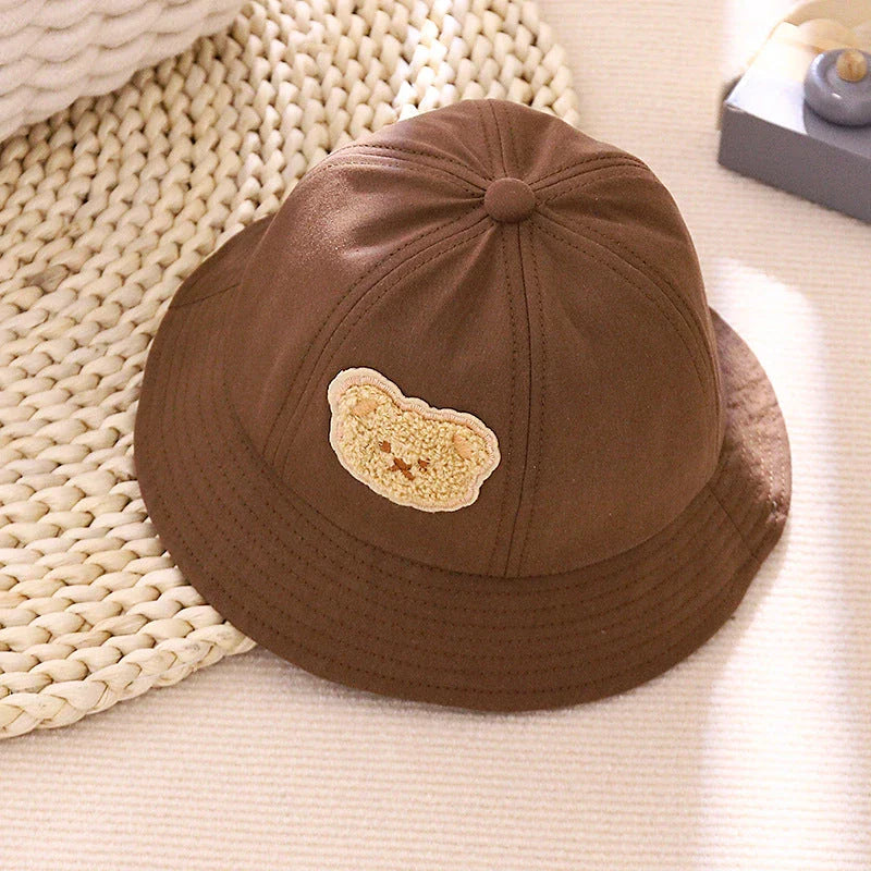 Cartoon Baby Hat in White Colour, Featuring a Playful Cartoon Pattern and Fitted Strap for a Comfortable Fit