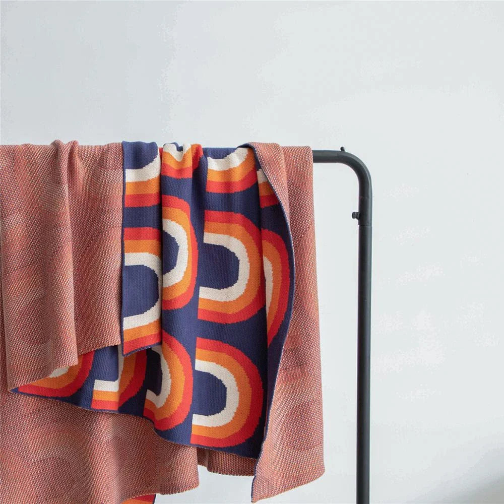 Cosy rainbow-patterned cotton knit throw blanket in various plaid and stripe designs, showcasing vibrant colours and a soft, comfortable texture.