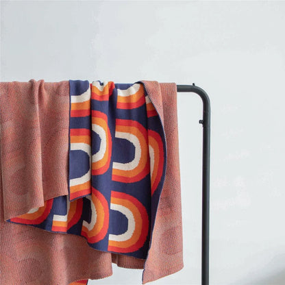 Cosy rainbow-patterned cotton knit throw blanket in various plaid and stripe designs, showcasing vibrant colours and a soft, comfortable texture.