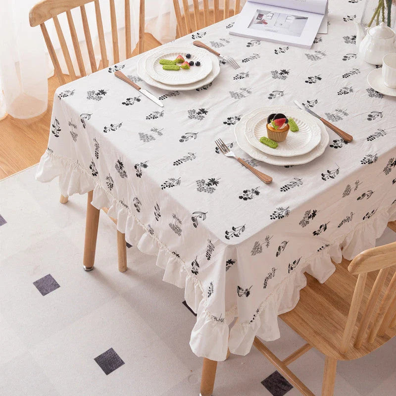 A high-quality cotton tablecloth with elegant floral embroidery and ruffled edges, creating a refined and charming dining experience.