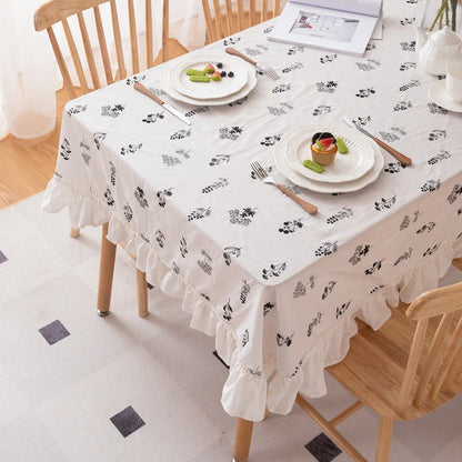 A high-quality cotton tablecloth with elegant floral embroidery and ruffled edges, creating a refined and charming dining experience.