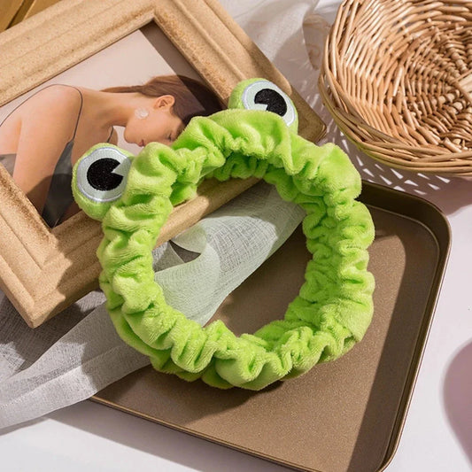 Charming frog-themed headband with plush coral fleece material and elastic band for a comfortable, customized fit