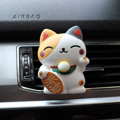 A black resin lucky cat car air freshener clipped onto a car vent, providing a refreshing fragrance and whimsical charm.