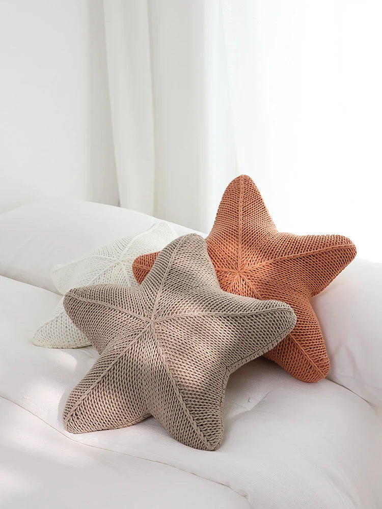 Artfully hand-knitted starfish-shaped cushion in a range of sophisticated colour options, providing plush comfort and coastal charm for any living space.