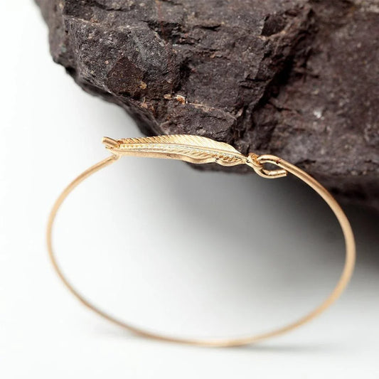 Elegant gold-coloured brass bracelet with a delicate falling leaf design, a nature-inspired accessory for everyday wear