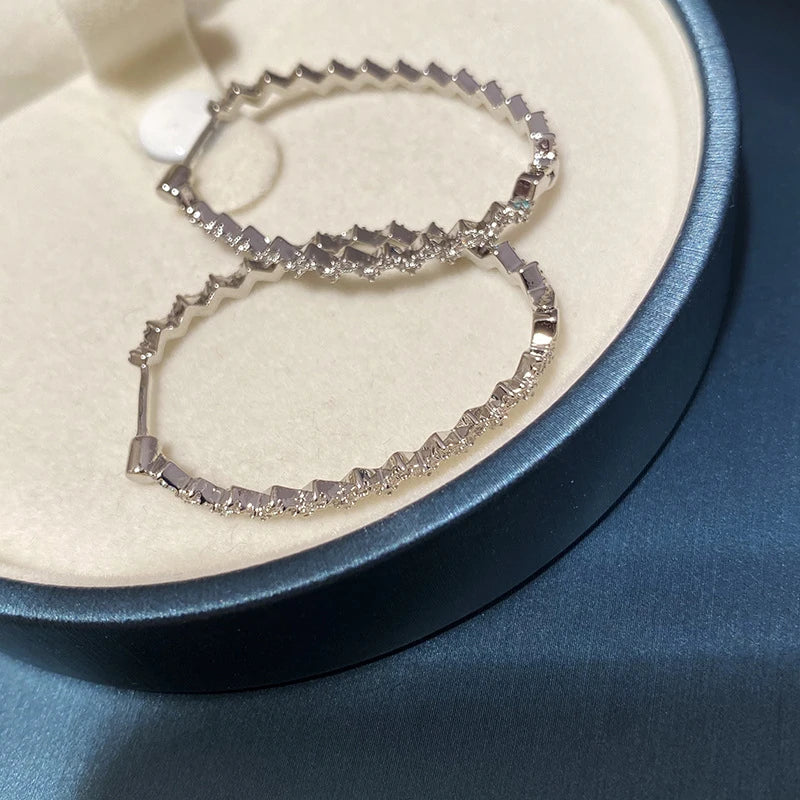 A pair of elegant sterling silver geometric earrings with a captivating wave-like pattern, inspired by the latest fashion trends in Japan and South Korea.