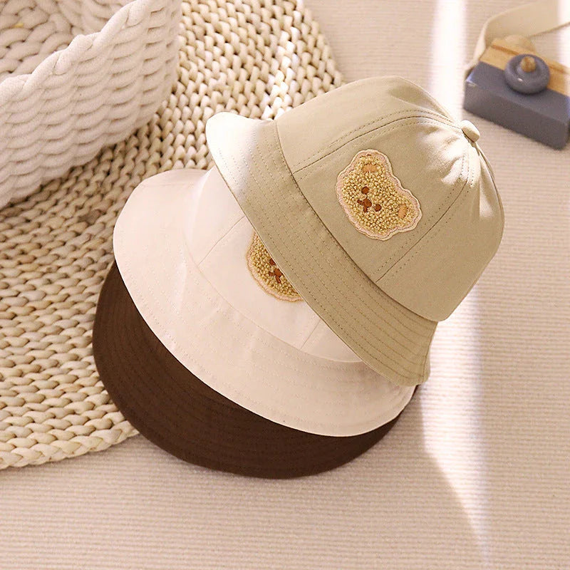 Cartoon Baby Hat in White Colour, Featuring a Playful Cartoon Pattern and Fitted Strap for a Comfortable Fit