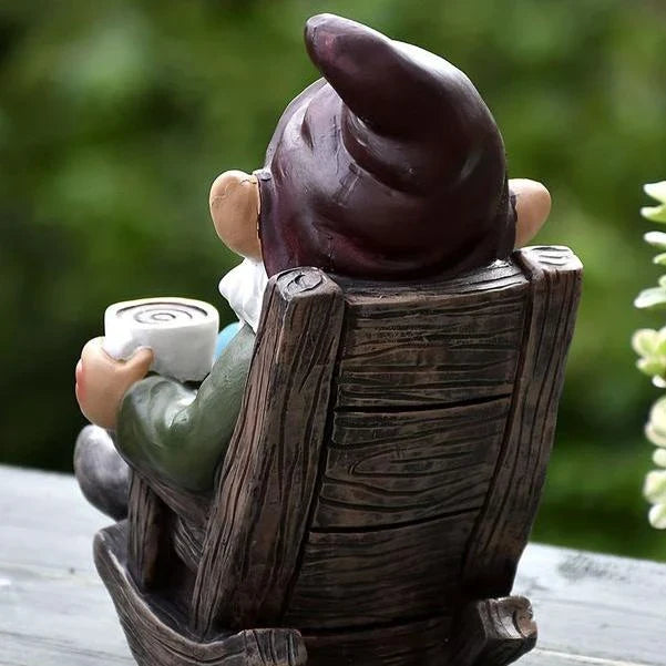 A charming garden gnome ornament made of durable resin, relaxing in a rocking chair and sipping tea, adding a whimsical touch to any outdoor space.