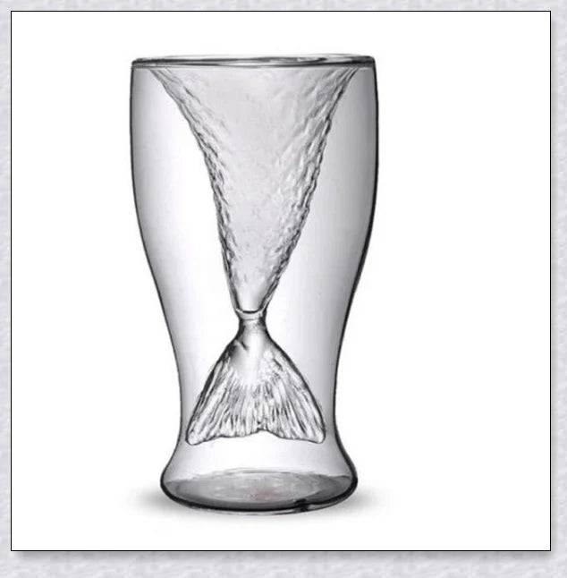 A transparent glass mug with a decorative mermaid tail design, perfect for enjoying a range of beverages in style.