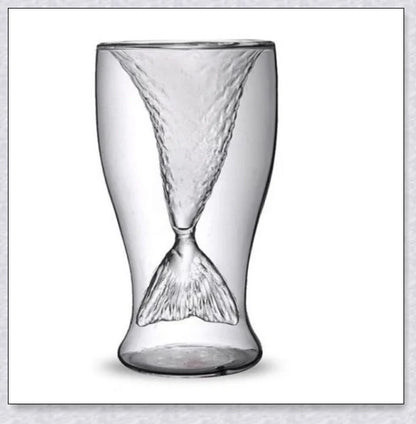 A transparent glass mug with a decorative mermaid tail design, perfect for enjoying a range of beverages in style.