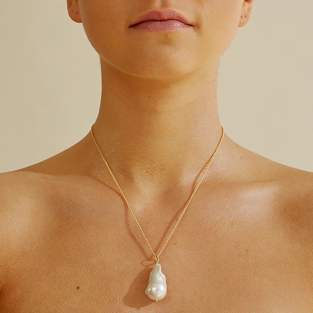 Elegant freshwater pearl necklace with a unique fish tail-shaped pendant and a delicate O-shaped chain
