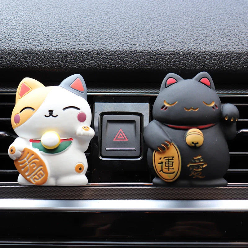 A black resin lucky cat car air freshener clipped onto a car vent, providing a refreshing fragrance and whimsical charm.