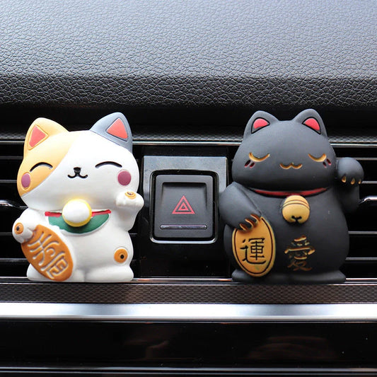 A black resin lucky cat car air freshener clipped onto a car vent, providing a refreshing fragrance and whimsical charm.