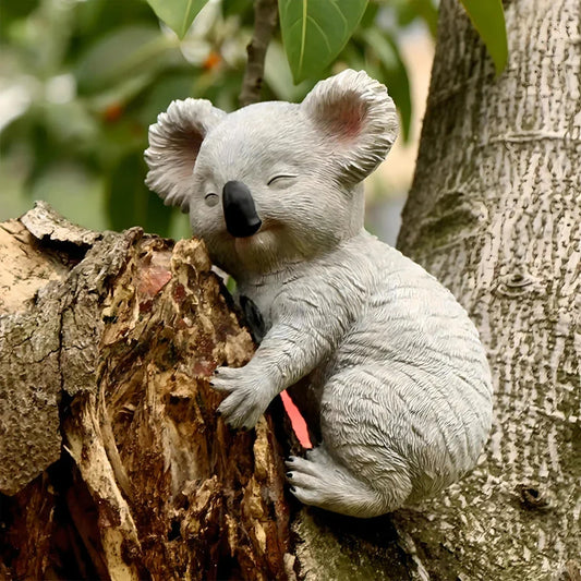 A lifelike grey resin koala statue climbing on a tree, adding a charming and whimsical touch to a garden or outdoor space