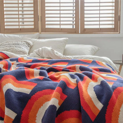 Cosy rainbow-patterned cotton knit throw blanket in various plaid and stripe designs, showcasing vibrant colours and a soft, comfortable texture.