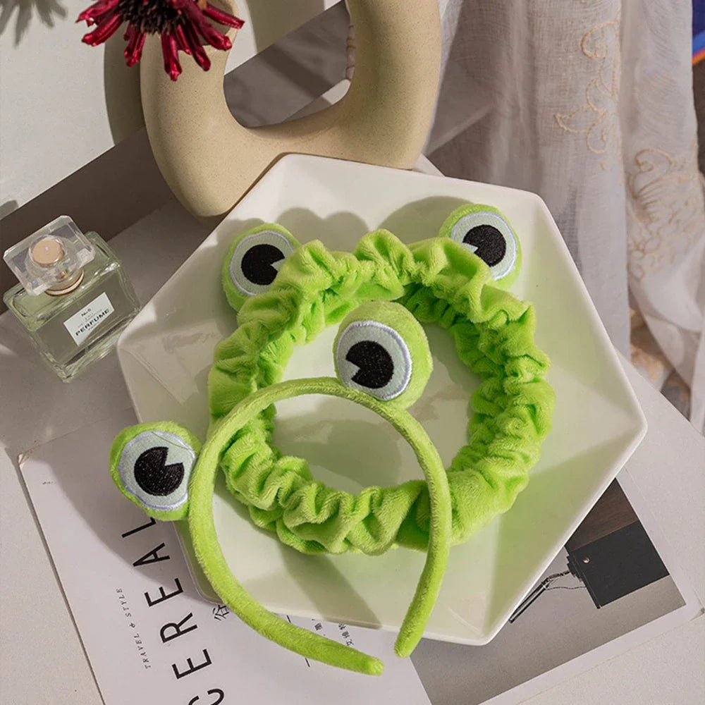 Charming frog-themed headband with plush coral fleece material and elastic band for a comfortable, customized fit