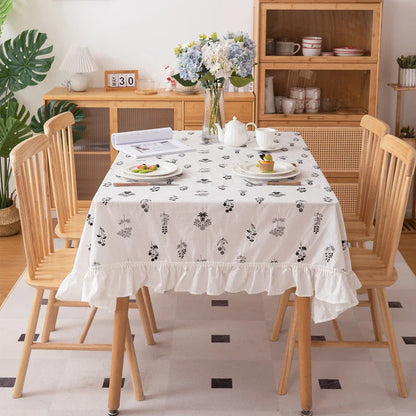 A high-quality cotton tablecloth with elegant floral embroidery and ruffled edges, creating a refined and charming dining experience.
