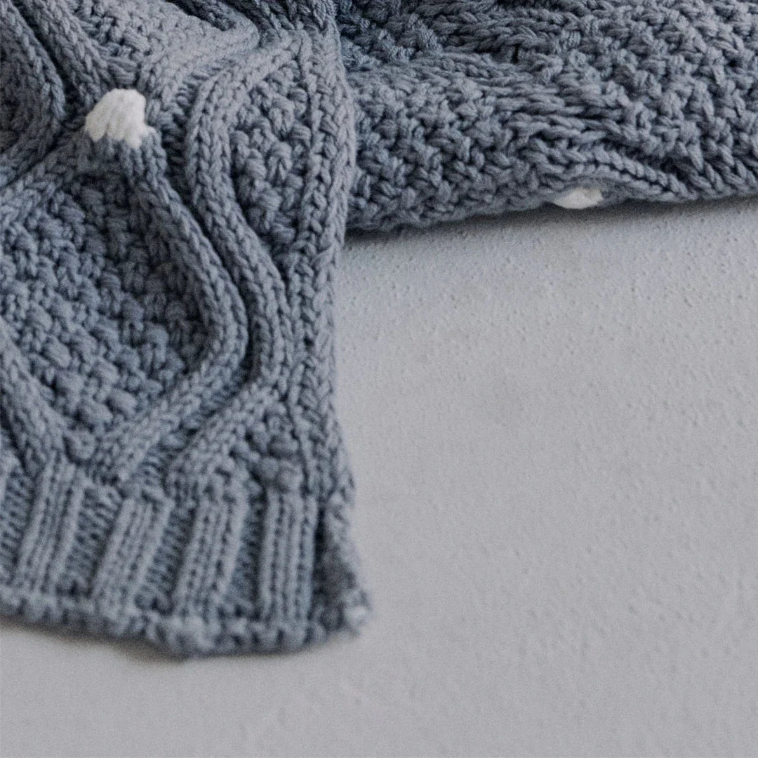 Cosy chunky knit blanket with charming pompoms in multiple sizes and colours for elegant home décor