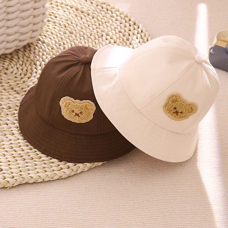 Cartoon Baby Hat in White Colour, Featuring a Playful Cartoon Pattern and Fitted Strap for a Comfortable Fit