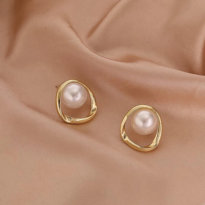 Elegant gold-coloured simulated pearl stud earrings with a distinctive geometric design