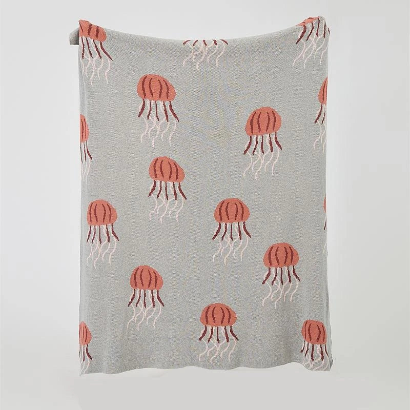 Cosy jellyfish-patterned cotton knit throw blanket in green and grey colours, showcasing its soft, plush texture and unique design.