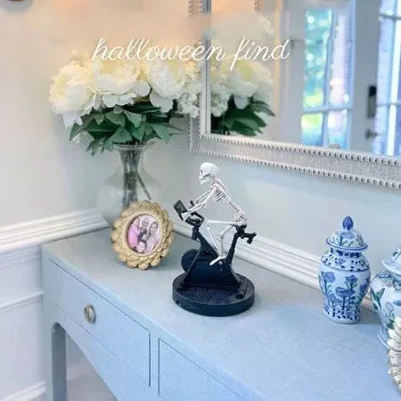 A delightful animatronic skeleton figure cycling, crafted with premium synthetic resin for a charming and durable home accent piece.