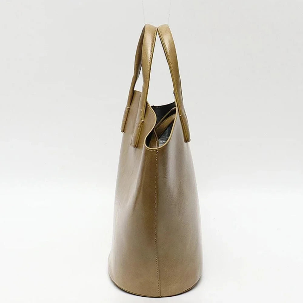 Elegant vegan leather tote bag with a unique bucket shape, short handles, and long straps for versatile carrying options