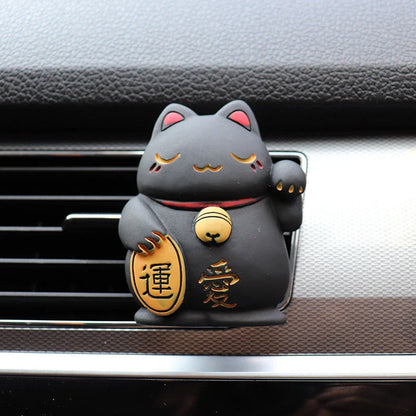 A black resin lucky cat car air freshener clipped onto a car vent, providing a refreshing fragrance and whimsical charm.