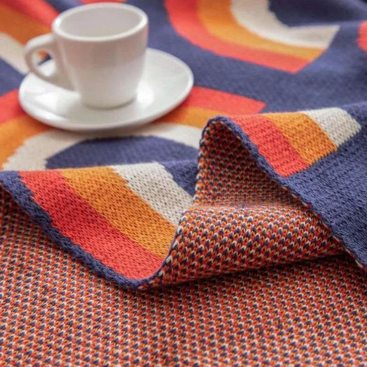 Cosy rainbow-patterned cotton knit throw blanket in various plaid and stripe designs, showcasing vibrant colours and a soft, comfortable texture.