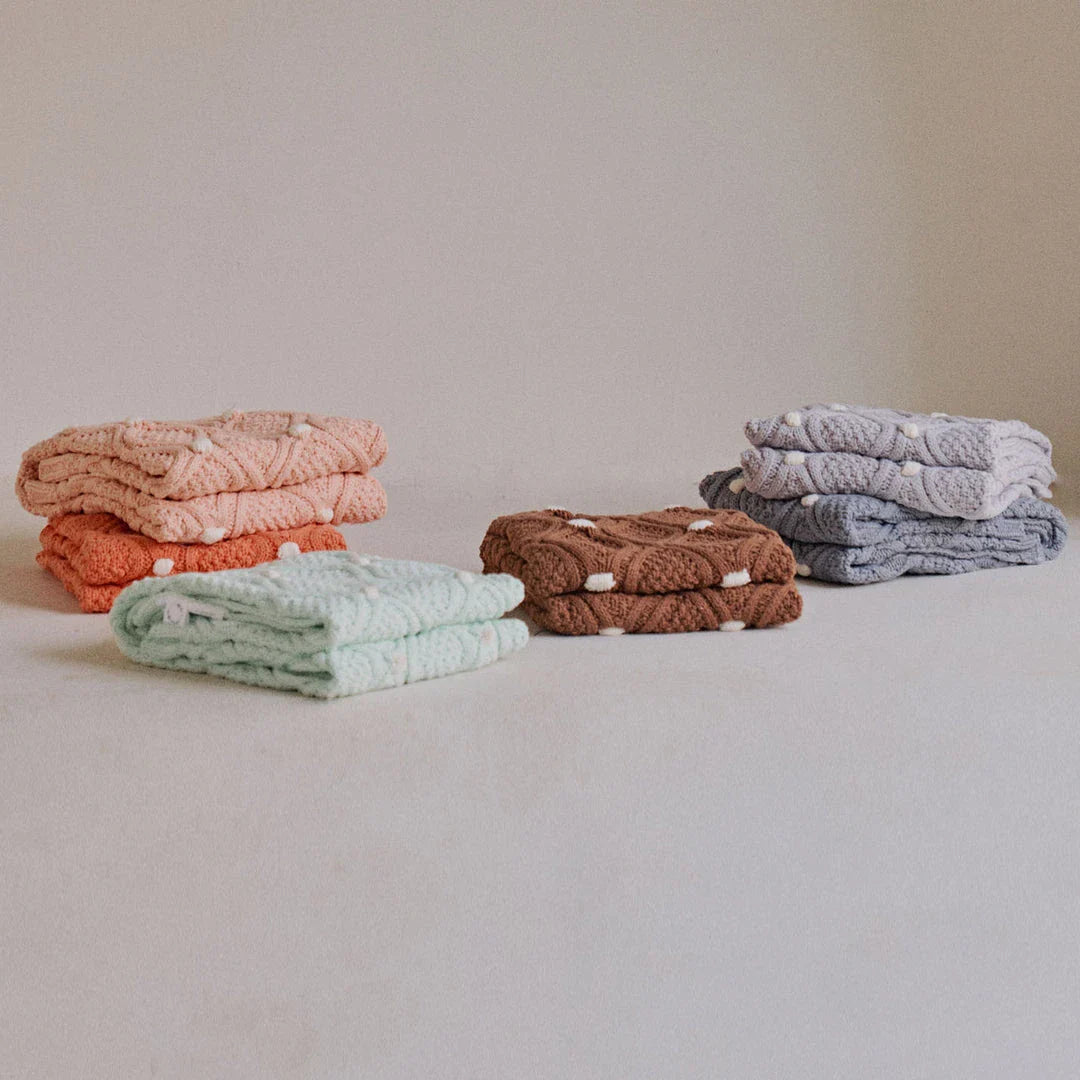 Cosy chunky knit blanket with charming pompoms in multiple sizes and colours for elegant home décor