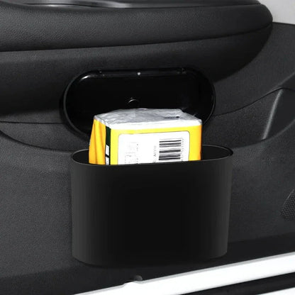 A compact black car bin with a press-type lid, designed to hang on the door panel and store garbage securely