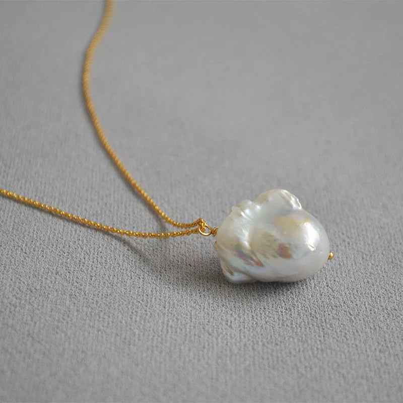 Elegant freshwater pearl necklace with a unique fish tail-shaped pendant and a delicate O-shaped chain