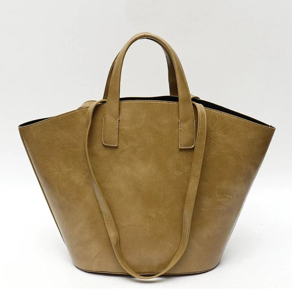 Elegant vegan leather tote bag with a unique bucket shape, short handles, and long straps for versatile carrying options