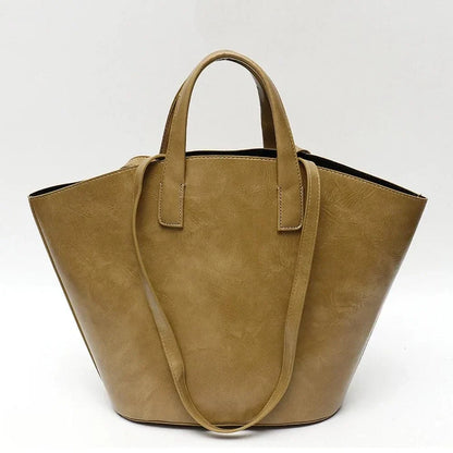 Elegant vegan leather tote bag with a unique bucket shape, short handles, and long straps for versatile carrying options