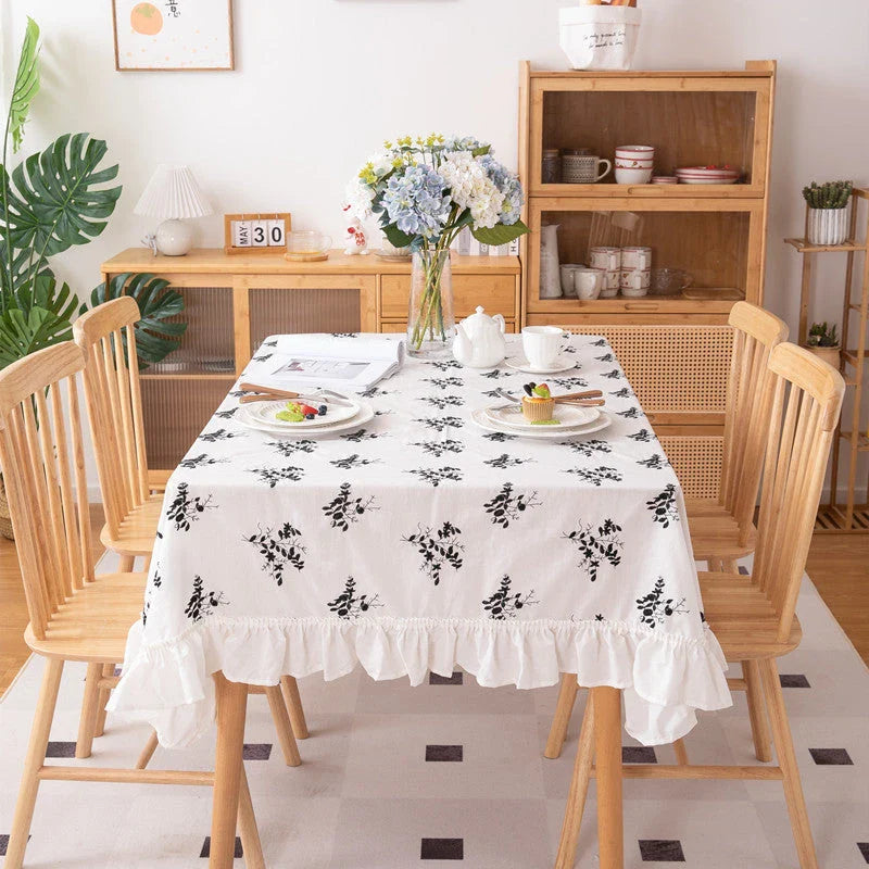A high-quality cotton tablecloth with elegant floral embroidery and ruffled edges, creating a refined and charming dining experience.