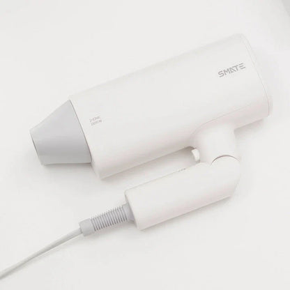 Compact and portable hair dryer with foldable handle, two-speed settings, and multiple nozzle positions for versatile styling