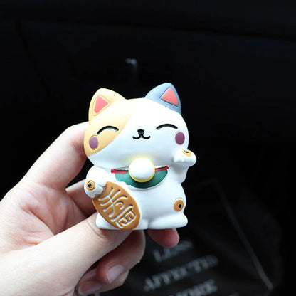 A black resin lucky cat car air freshener clipped onto a car vent, providing a refreshing fragrance and whimsical charm.