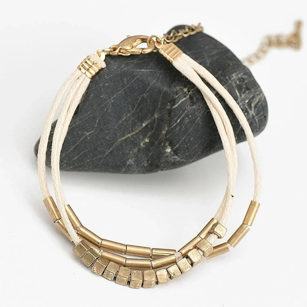 Elegant layered bracelet with beige leather and gold-coloured beads, a versatile accessory for modern British style