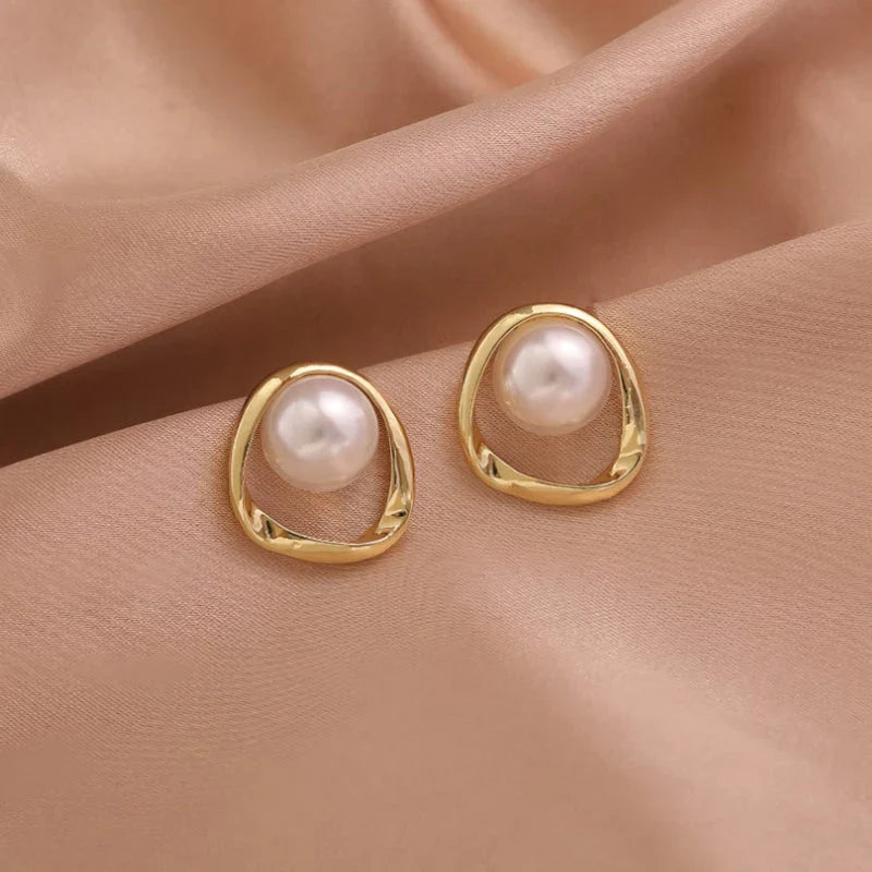 Elegant gold-coloured simulated pearl stud earrings with a distinctive geometric design