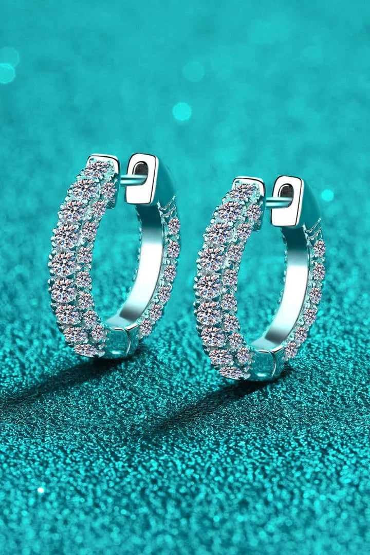 Pair of elegant sterling silver huggie earrings adorned with dazzling moissanite stones, showcasing a minimalist and sophisticated design.