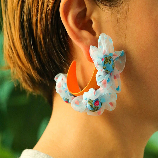 Handmade floral earrings in various sizes, featuring intricate fabric and alloy designs inspired by the British countryside.