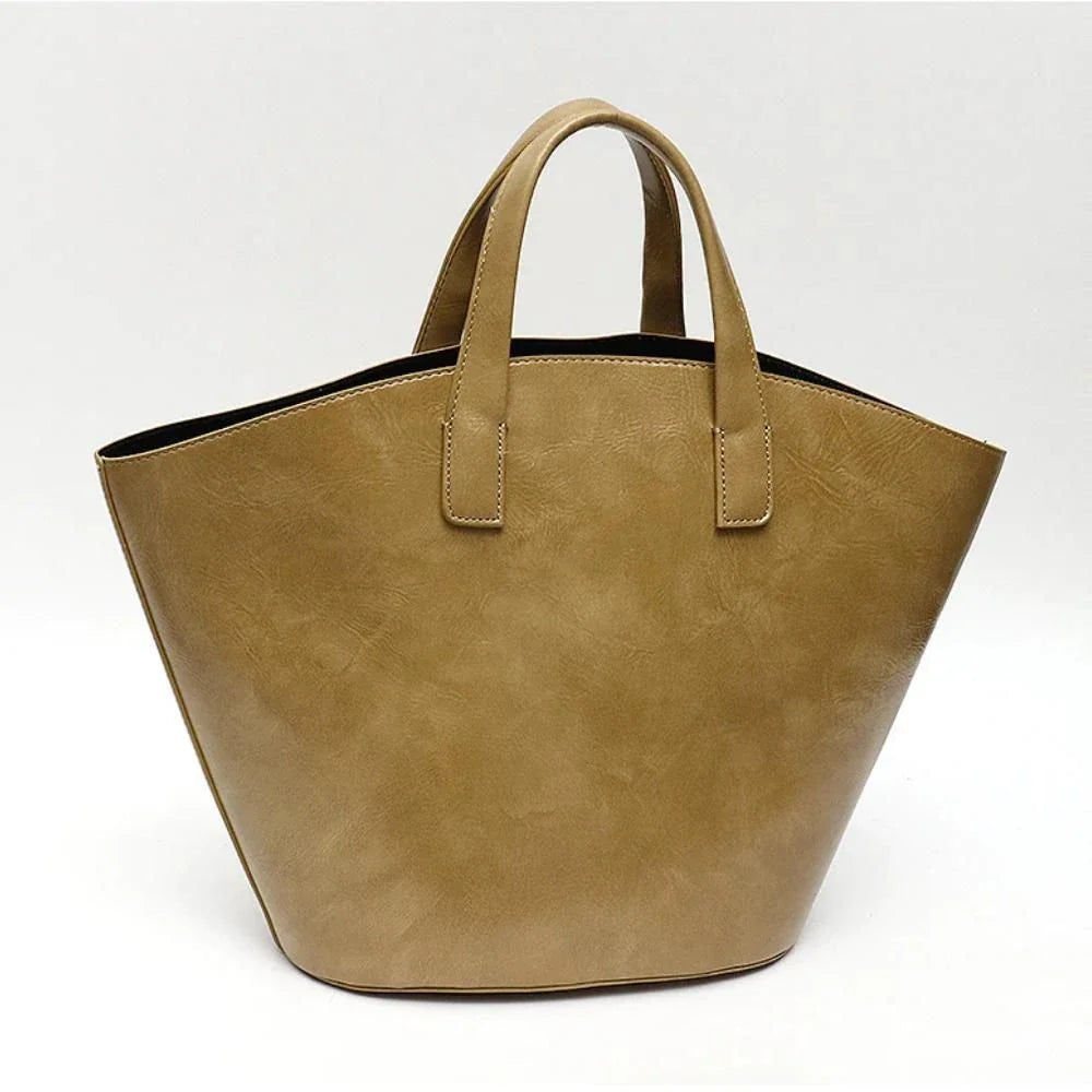 Elegant vegan leather tote bag with a unique bucket shape, short handles, and long straps for versatile carrying options