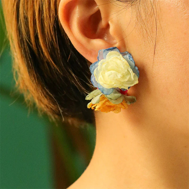 Handmade floral earrings in various sizes, featuring intricate fabric and alloy designs inspired by the British countryside.