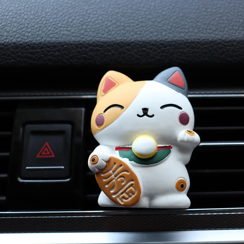 A black resin lucky cat car air freshener clipped onto a car vent, providing a refreshing fragrance and whimsical charm.