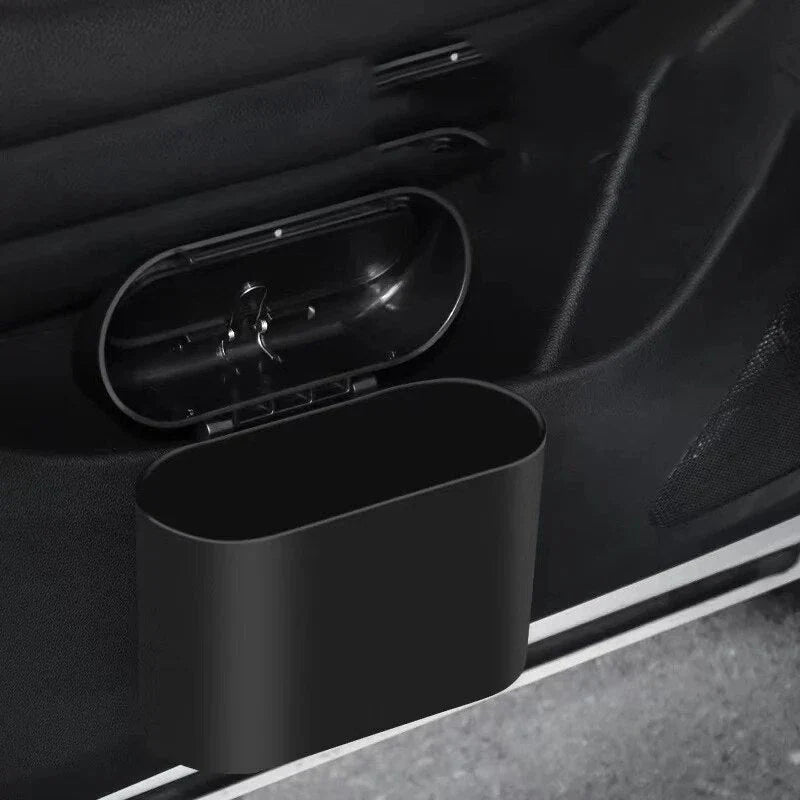 A compact black car bin with a press-type lid, designed to hang on the door panel and store garbage securely