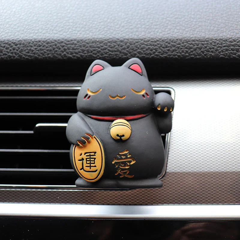 A black resin lucky cat car air freshener clipped onto a car vent, providing a refreshing fragrance and whimsical charm.