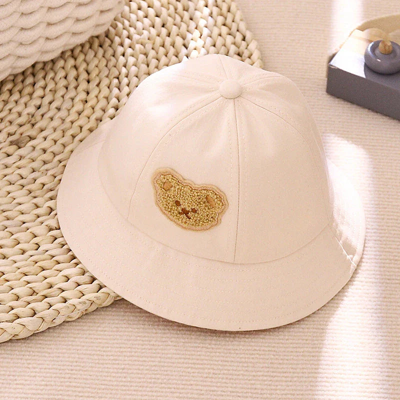 Cartoon Baby Hat in White Colour, Featuring a Playful Cartoon Pattern and Fitted Strap for a Comfortable Fit